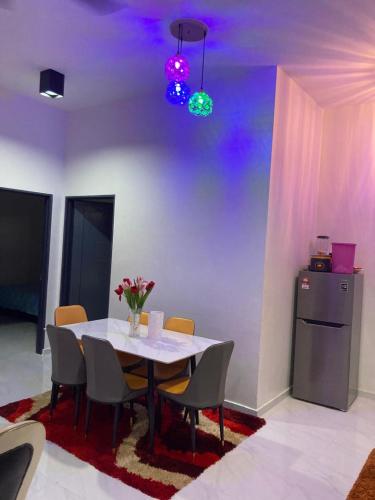 a dining room with a table with chairs and a refrigerator at Homestay Darul Bestari Cemerlang in Kampong Pak Sabah