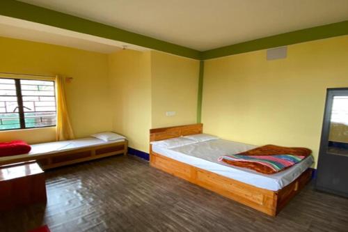 a bedroom with two beds in a room with green walls at Golden Apple Garden Homestay by StayApart in Kalimpong