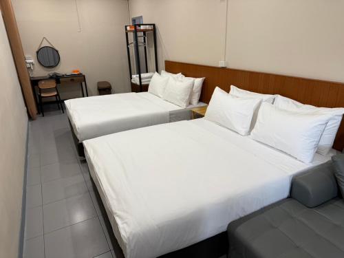 two beds in a hotel room with white sheets at Achcha hotel - itsaraphap MRT station - Wat Arun in Bangkok