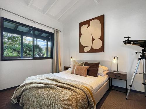 a bedroom with a bed with a camera on a tripod at Clifftop cottage escape with breathtaking views in Wentworth Falls