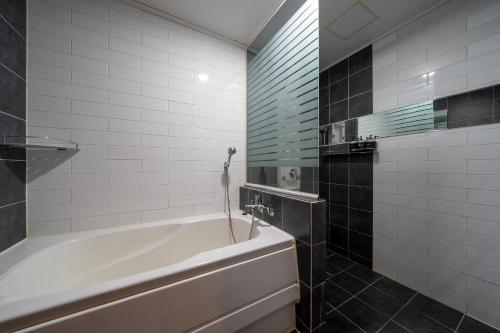 a bathroom with a white tub and a mirror at Gong-Ju TouristHotel INK in Gongju