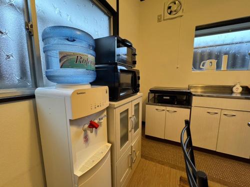 a refrigerator with a bucket on top of it in a kitchen at Yufuin Wasaku in Yufuin