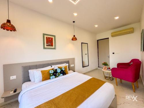 a bedroom with a large bed and a red chair at The Neeraj River Forest Resort Ayurvedic Wellness Center in Rishīkesh