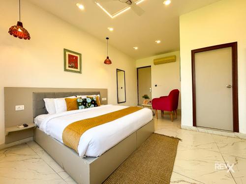 a bedroom with a large bed and a red chair at The Neeraj River Forest Resort Ayurvedic Wellness Center in Rishīkesh