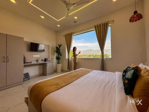 a woman standing in a bedroom looking out the window at The Neeraj River Forest Resort Ayurvedic Wellness Center in Rishīkesh