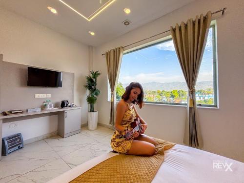 a woman sitting on a bed in a room with a window at The Neeraj River Forest Resort Ayurvedic Wellness Center in Rishīkesh