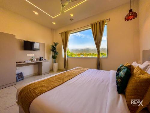 a bedroom with a large bed with a large window at The Neeraj River Forest Resort Ayurvedic Wellness Center in Rishīkesh