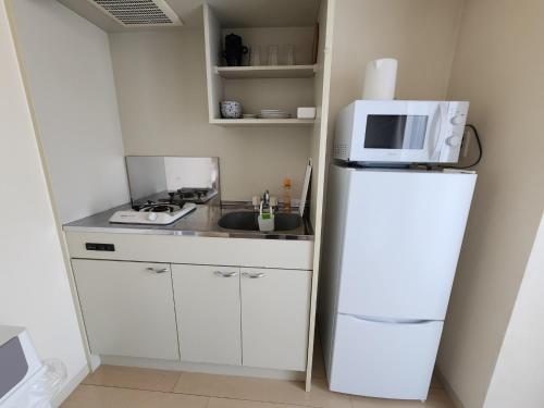 a small kitchen with a white refrigerator and a microwave at COCONE HOUSE Twin bedroom in Osaka