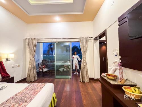 a hotel room with a woman standing outside a window at The Neeraj River Forest Resort Ayurvedic Wellness Center in Rishīkesh