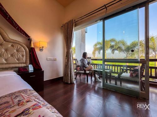 a woman sitting in a chair in a room with a large window at The Neeraj River Forest Resort Ayurvedic Wellness Center in Rishīkesh
