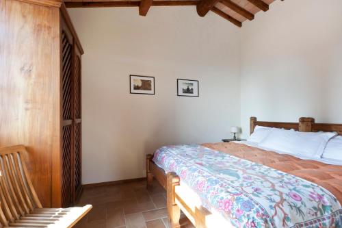 a bedroom with a large bed and a chair at Casale Pundarika in Riparbella
