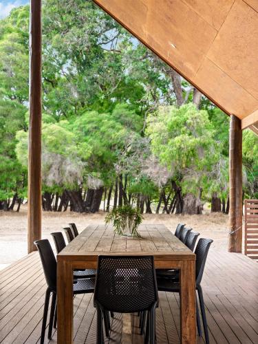 a wooden table and chairs on a deck with trees at Caves Farm Guest House in Cowaramup