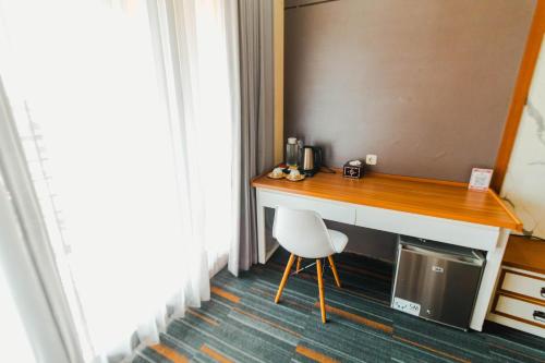 a desk in a hotel room with a chair next to a window at De Balen Soultan Hotel in Puyung