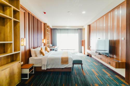 a hotel room with a bed and a flat screen tv at De Balen Soultan Hotel in Puyung