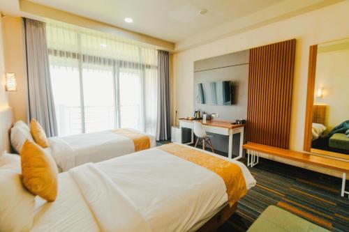 a hotel room with two beds and a desk at De Balen Soultan Hotel in Puyung