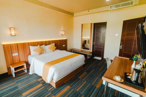 a hotel room with a large bed and a television at De Balen Soultan Hotel in Puyung