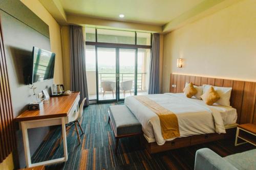 a hotel room with a bed and a desk and a window at De Balen Soultan Hotel in Puyung