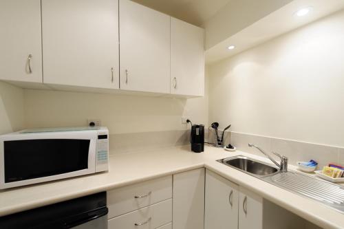 a white kitchen with a sink and a microwave at Montfort Manor in Traralgon