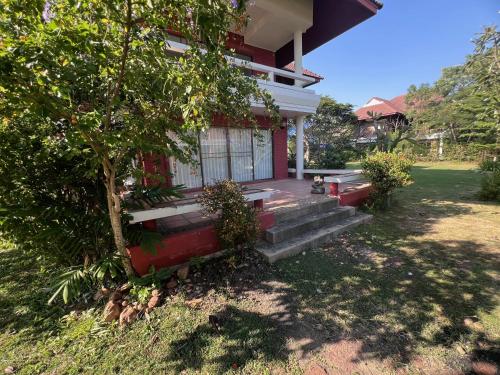 a dog sitting on the porch of a house at Baan Plumeria บ้านภูมิเรีย in Phetchaburi