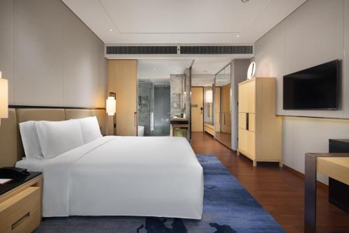 a bedroom with a large white bed and a television at New World Beijing Hotel in Beijing