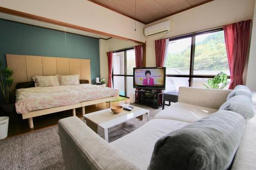 a living room with a bed and a tv at Nikko Kinugawa Stay in Nikko