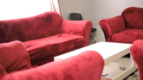 a living room with red chairs and a couch at Rustic Gardens Bed & Breakfast Kitunzi Lungujja in Kampala