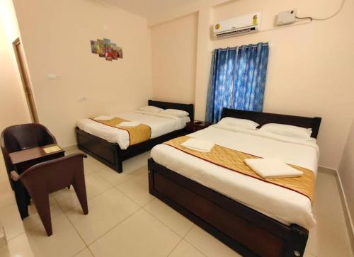 a hotel room with two beds and a chair at La township stay in Puducherry