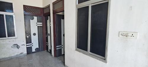an empty room with two windows and a door at Shree Krishna Guest House in Rīngas