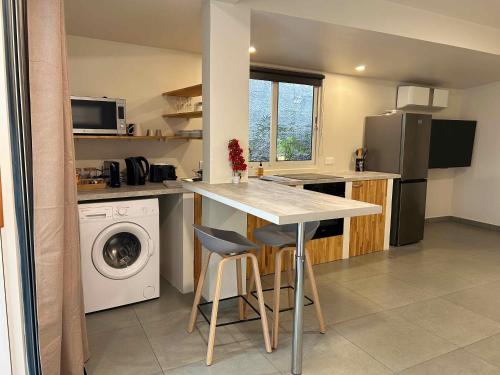a kitchen with a table and a washing machine at Lodge Tahiti in Punaauia