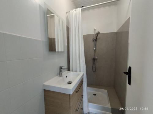 une salle de bain blanche avec un lavabo et une douche dans l'établissement A 150m de la plage, Maison moderne et spacieuse pour 7 personnes, à Les Sables Vignier