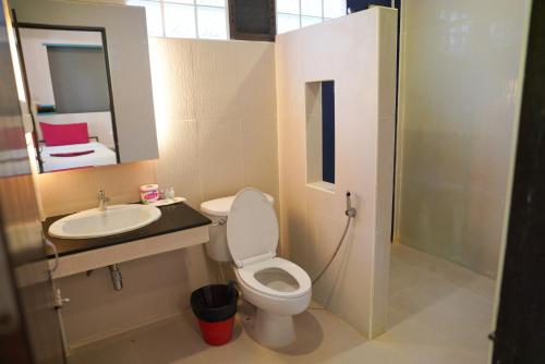 a bathroom with a toilet and a sink and a mirror at Tok Little Hut in Rayong