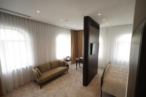 a living room with a couch and a bed at Kainar Hotel in Shymkent