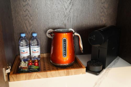 an orange tea kettle and bottles of water on a wooden tray at Kainar Hotel in Shymkent