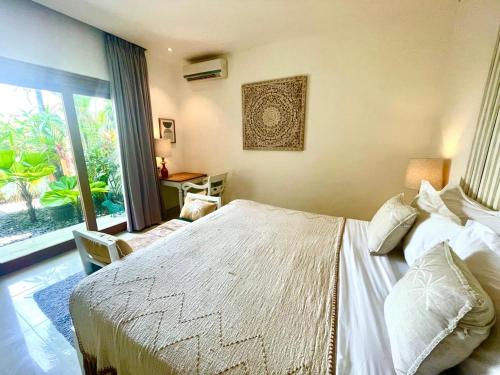 a bedroom with a bed and a large window at La Belle Villa in Seminyak