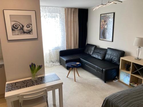 a living room with a black leather couch at Apartament 4 You in Swarzędz