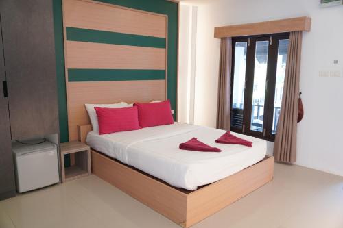 a bedroom with a bed with red pillows on it at Tok Little Hut in Rayong