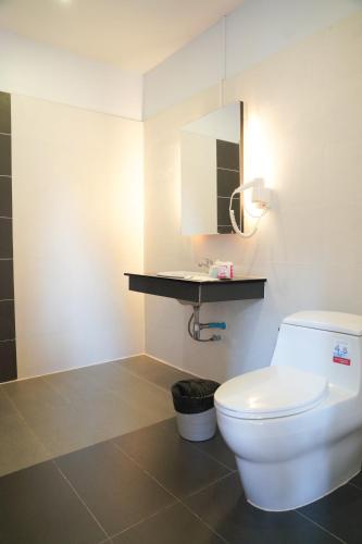 a bathroom with a white toilet and a mirror at Tok Little Hut in Rayong