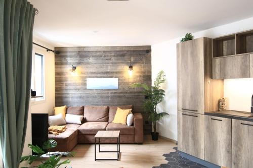 een woonkamer met een bank en een houten muur bij Le Refuge Tropical Taine in Annecy