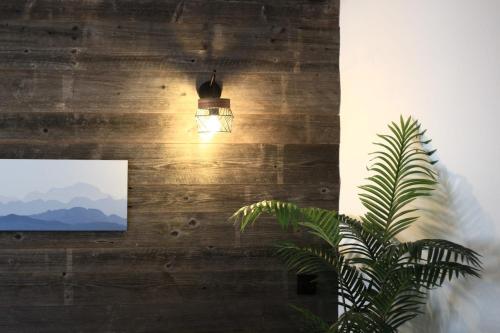 une lumière suspendue à un mur à côté d'une plante dans l'établissement Le Refuge Tropical Taine, à Annecy