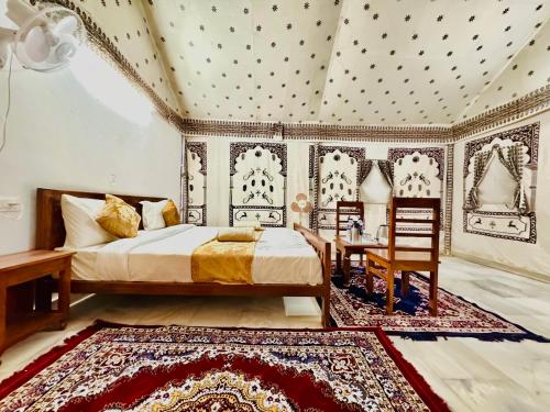a bedroom with a bed and a table and chairs at DESERT OVERNIGHT LUXURY CAMP & ReSORT in Jaisalmer