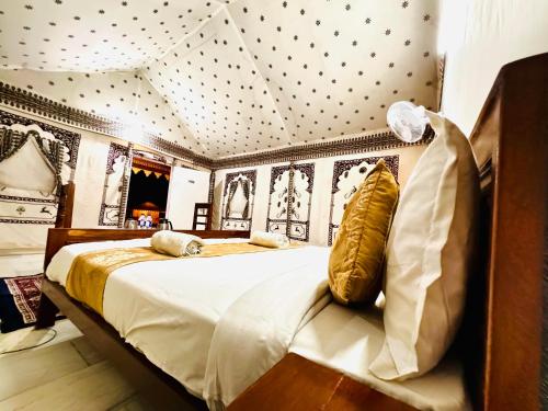 a bedroom with a bed with white sheets and gold pillows at DESERT OVERNIGHT LUXURY CAMP & ReSORT in Jaisalmer