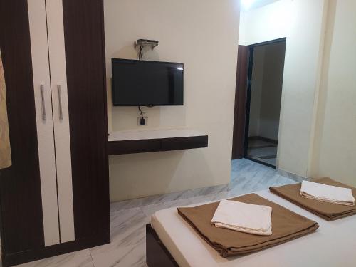 a room with a tv and a bed with towels at Sea Winds Hotel, Guhagar in Ratnagiri