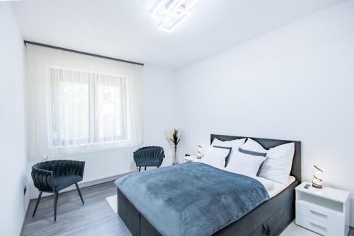 a white bedroom with a bed and two chairs at Sunrise Palace in Sarud
