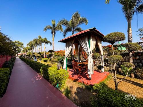 a gazebo in a park with palm trees at The Neeraj River Forest Resort Ayurvedic Wellness Center in Rishīkesh