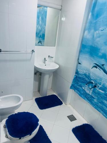 a bathroom with a sink and a toilet and blue rugs at Panoramic Sea View Studio in Abu Dhabi
