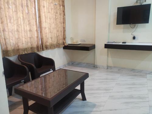 a room with a table and chairs and a television at Sea Winds Hotel, Guhagar in Ratnagiri
