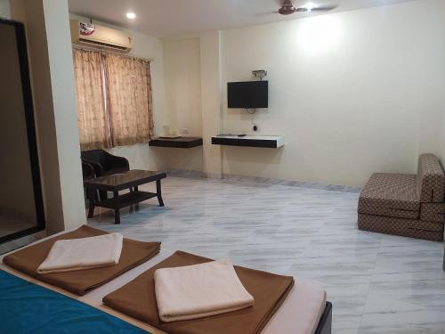 a living room with a couch and a tv at Sea Winds Hotel, Guhagar in Ratnagiri