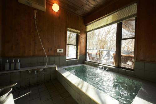 a large bath tub in a bathroom with a window at プライベートリゾート富士 in Yamanakako