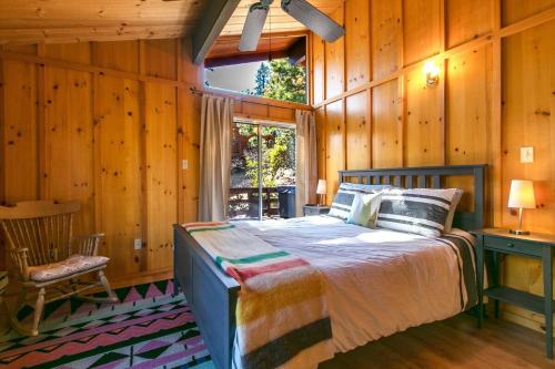 a bedroom with a bed in a room with wooden walls at RACC00N Rock Charming Hot Tub Cabin in Pine Cove