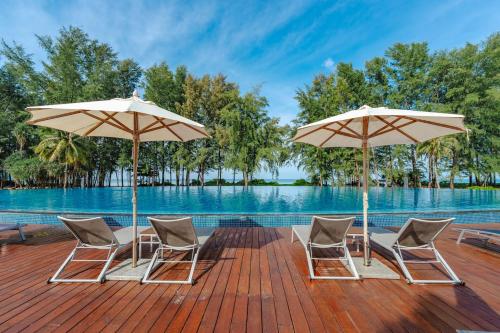 a deck with chairs and umbrellas next to the water at Splash Beach Resort Phuket, Family-Friendly Beachfront Water Park Resort in Mai Khao Beach